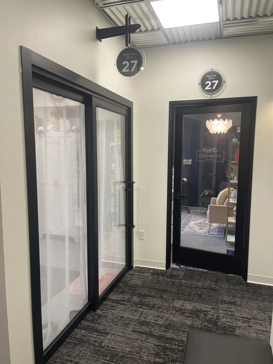 Studio 27 at Sola Salon Studios in Erie, PA — glass doors to Chelsea on the left and the dark Formosa Hair Studio door to Katie on the right